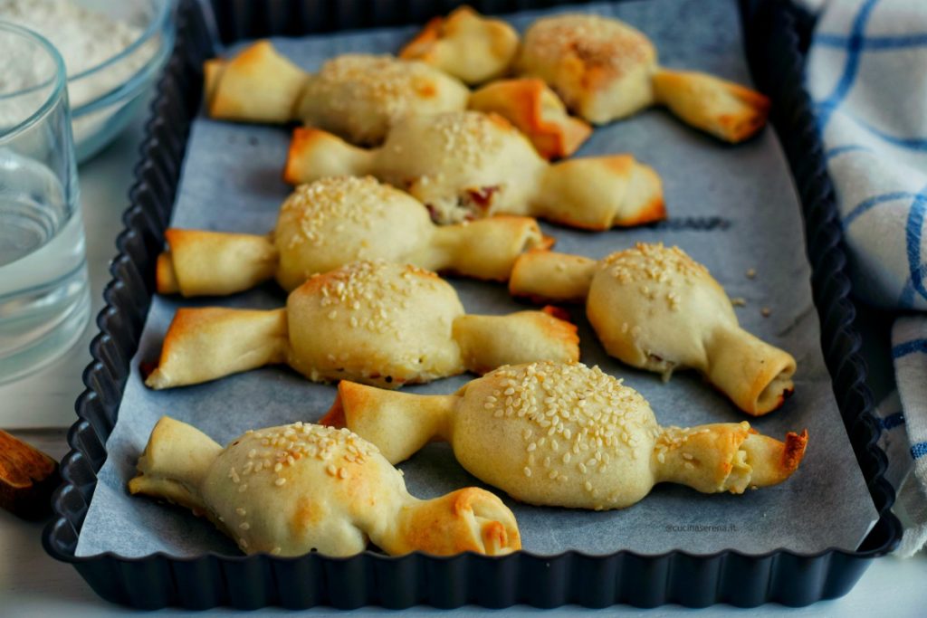 Caramelle di pasta matta è un antipasto in cui alla sfoglia di pasta matta viene farcita e data la forma della caramella. Nella foto sono disposte su una teglia da forno in obbliquo l'una all'altra. Sulla sinistra come sfondo alcuni ingredienti della ricetta