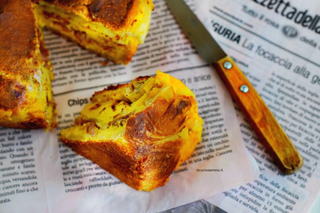 nella foto una fetta tagliata della pizza chiena, adagiata su un foglio di giornale. Poco dietro si intravede la torta rustica con una parte mancante e sulla destra un coltello