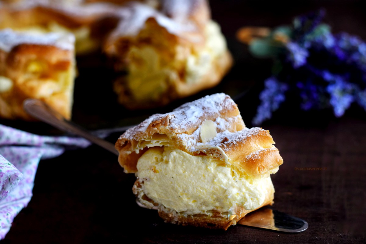 Fetta di paris brest adagiata su una paletta per dolci. Dalla foto si vede bene la crema mousseline in mezzo a due strati di pasta choux cotta