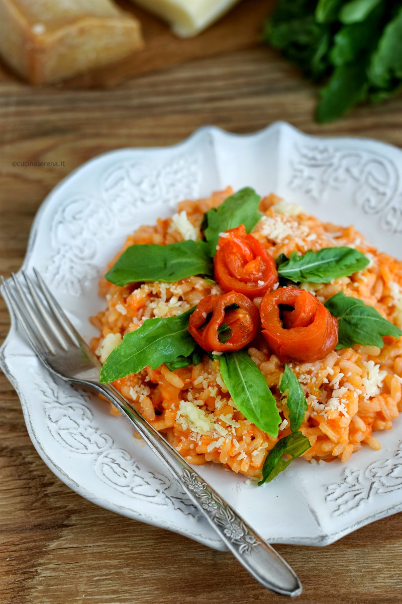 Risotto peperoni e rucola ai due formaggi servitocon decorazione di peperoni a forma di riso, foglie di rucola, formaggio grattugiato e riccioli di caciottina