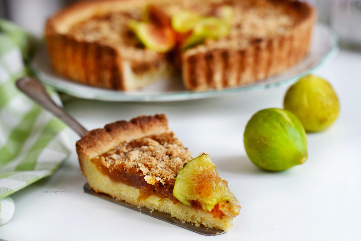 Crostata di confettura di fichi e crumble di amaretti imbevuti nel rum. Nella foto fetta della crostata con sopra una fettina di fico fresca