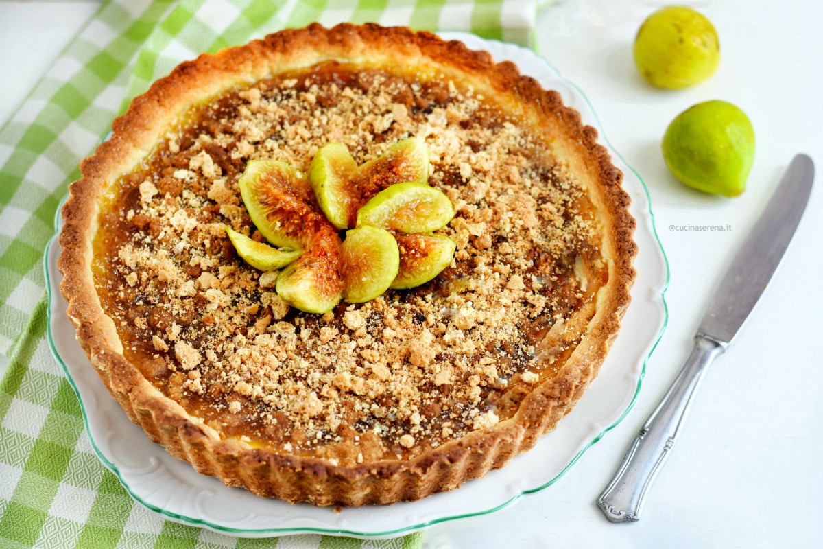 Figues jam crust with amaretti cookies - the crust in in a dish on the table a knife and two fresh figues fruit