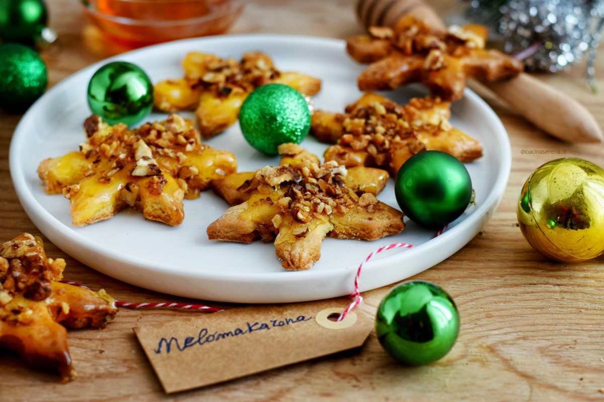 melamakarona biscotti natalizi greci, nella foto presentati in un piatto a forma di stella con decorazioni natalizie attorno