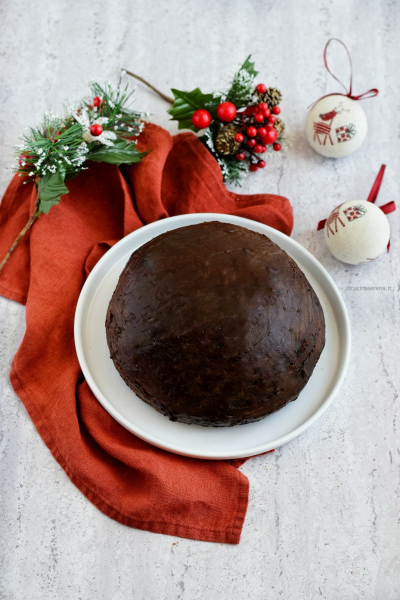 Parrozzo dolce tipico abruzzese ricoperto di cioccolato nella foto su un piatto bianco sotto un tovagliolo color ruggine, due palline di natale sulla destra del piatto