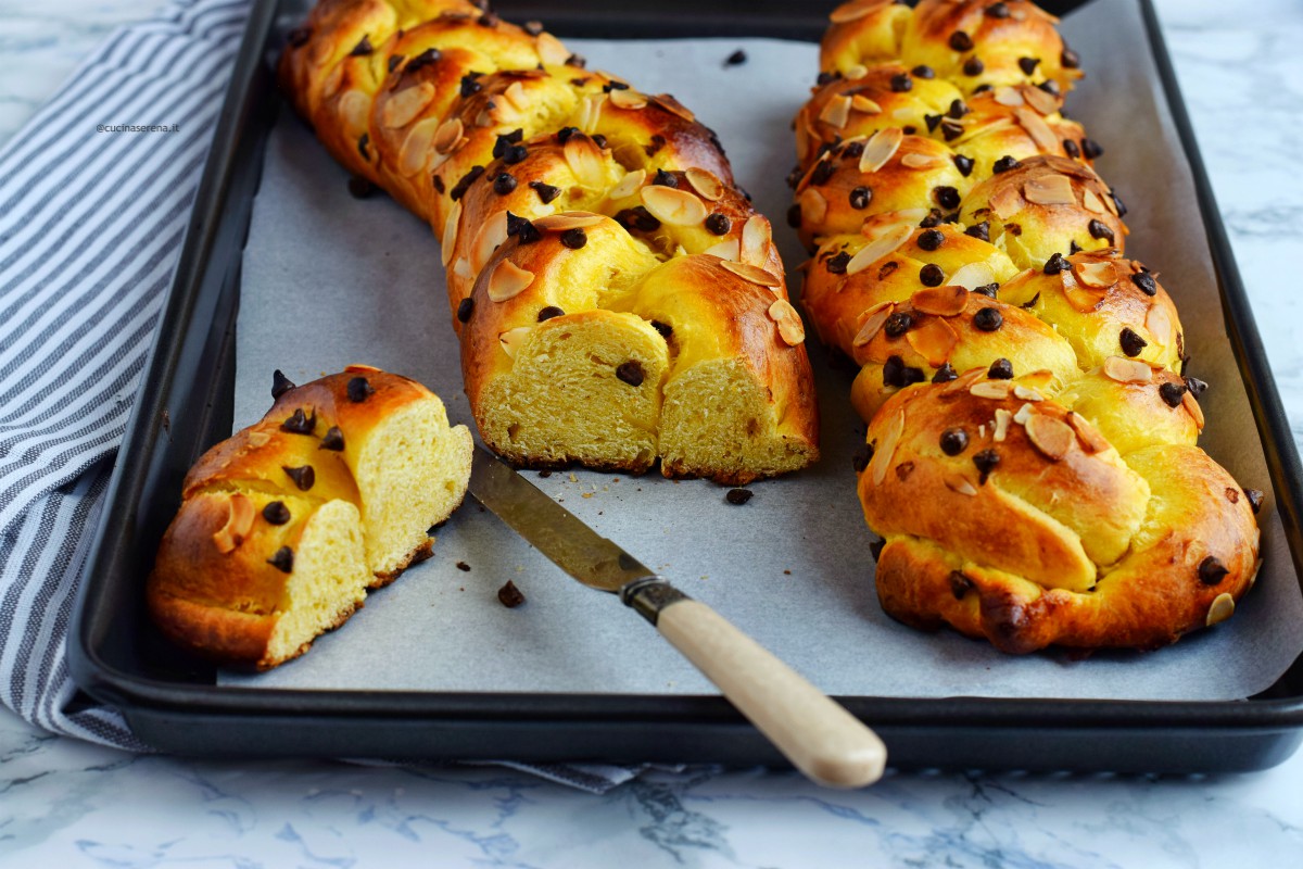 Tsoureki pane pasquale greco con cioccolato e mandorle intrecciato. Nella foro presentato in una teglia , le trecce sono due una delle quali è tagliata e lascia vedere la stuttura interna del pan brioche