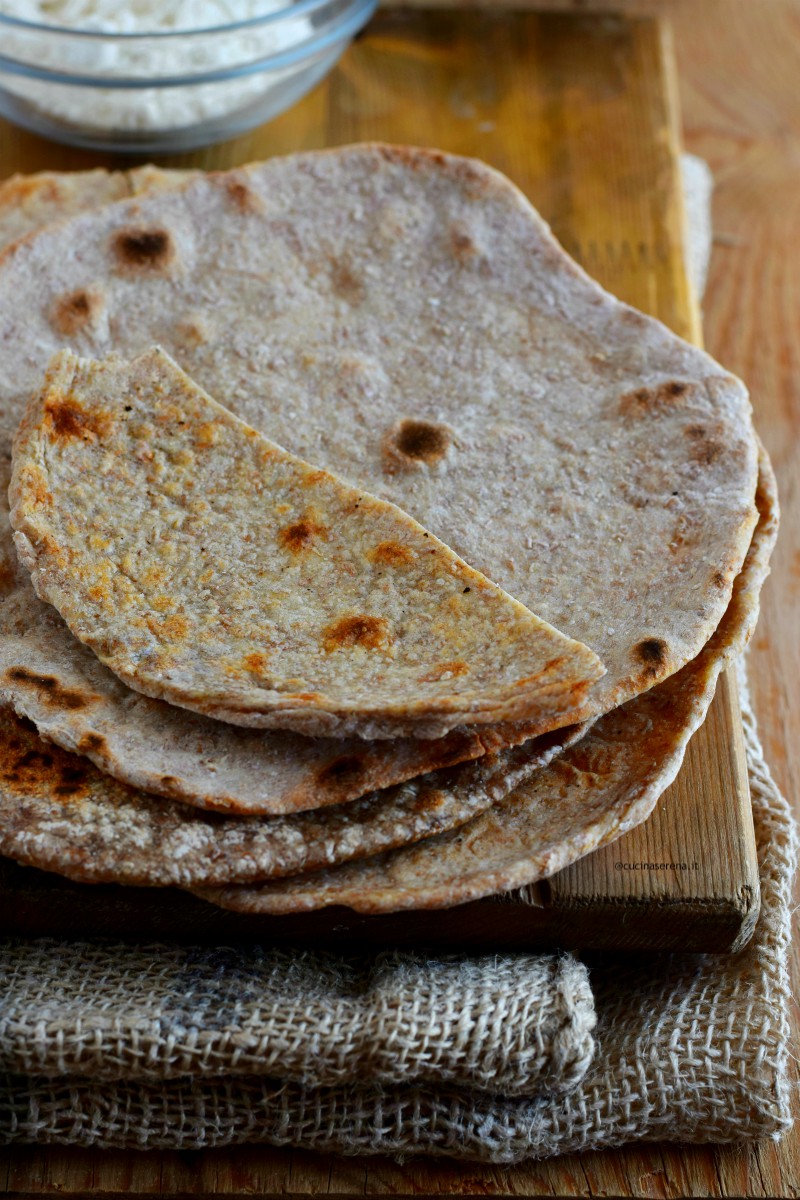 Chapati: pane indiano senza lievito fatto soltnato con farina integrale, acqua e sale dalla forma rotonda. Nella foto tre sfoglie disposte una sopra l'altra i cima un pezzetto tagliato