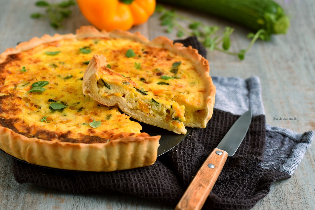 Torta rustica di pasta matta con verdure estive nella foto con una fetta tagliate posizionata in obliquo sopra la torta