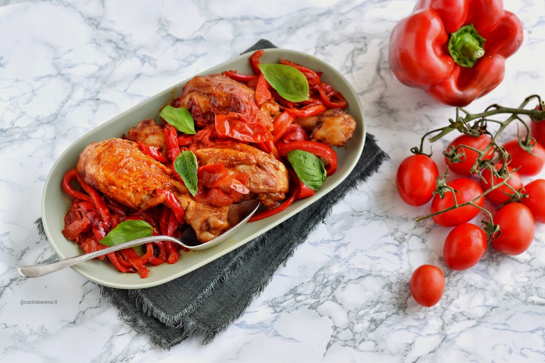 Pollo con peperoni alla romana nella foto pollo a pezzi presentato in un vassoio con peperoni rossi