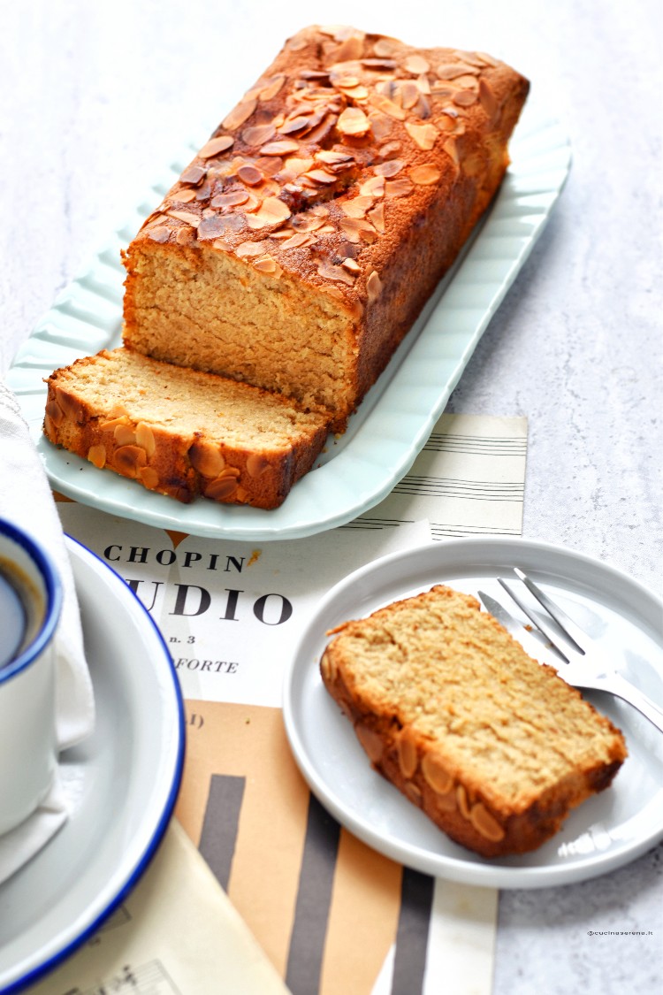 Plumcake agli allbumi senza latte e burro ricoperto di scaglie di mandorle nella foto è su un vassoio con una fetta tagliata da cui si vede la texture interna